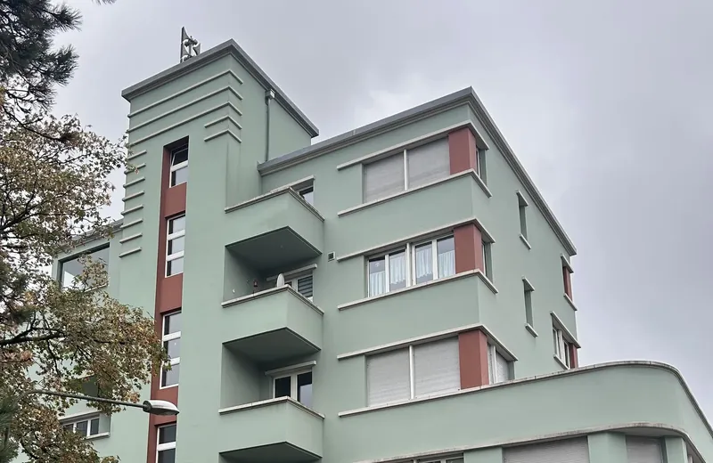 Fassade des Touringhauses mit Balkonen und rotem Fensterband
